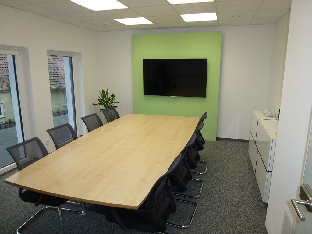 Konferenzraum ausgestattet mit großem Tisch, Stühlen und Bildschirm
